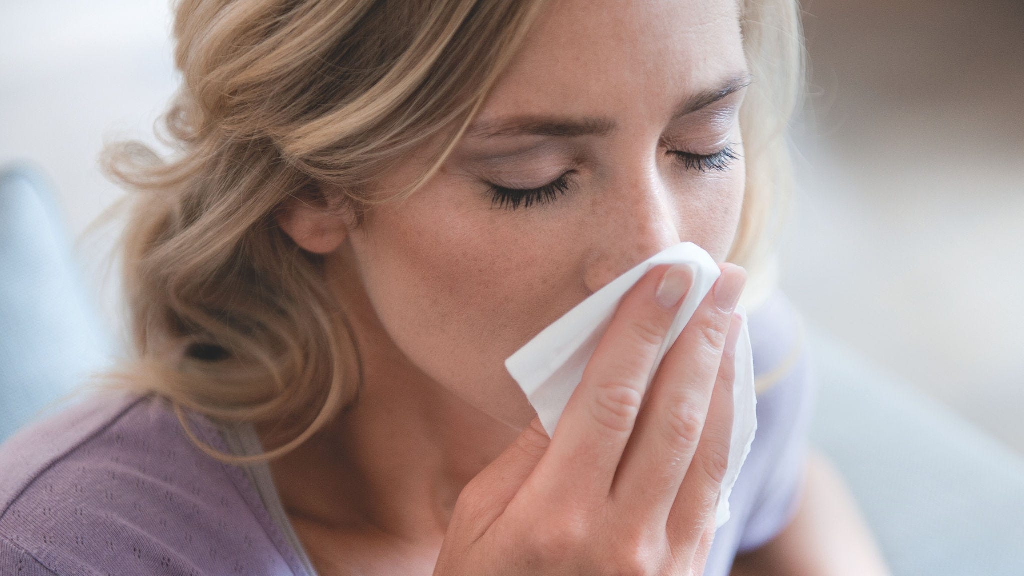 Kvinde, der pudser næse på grund af pollenallergi.