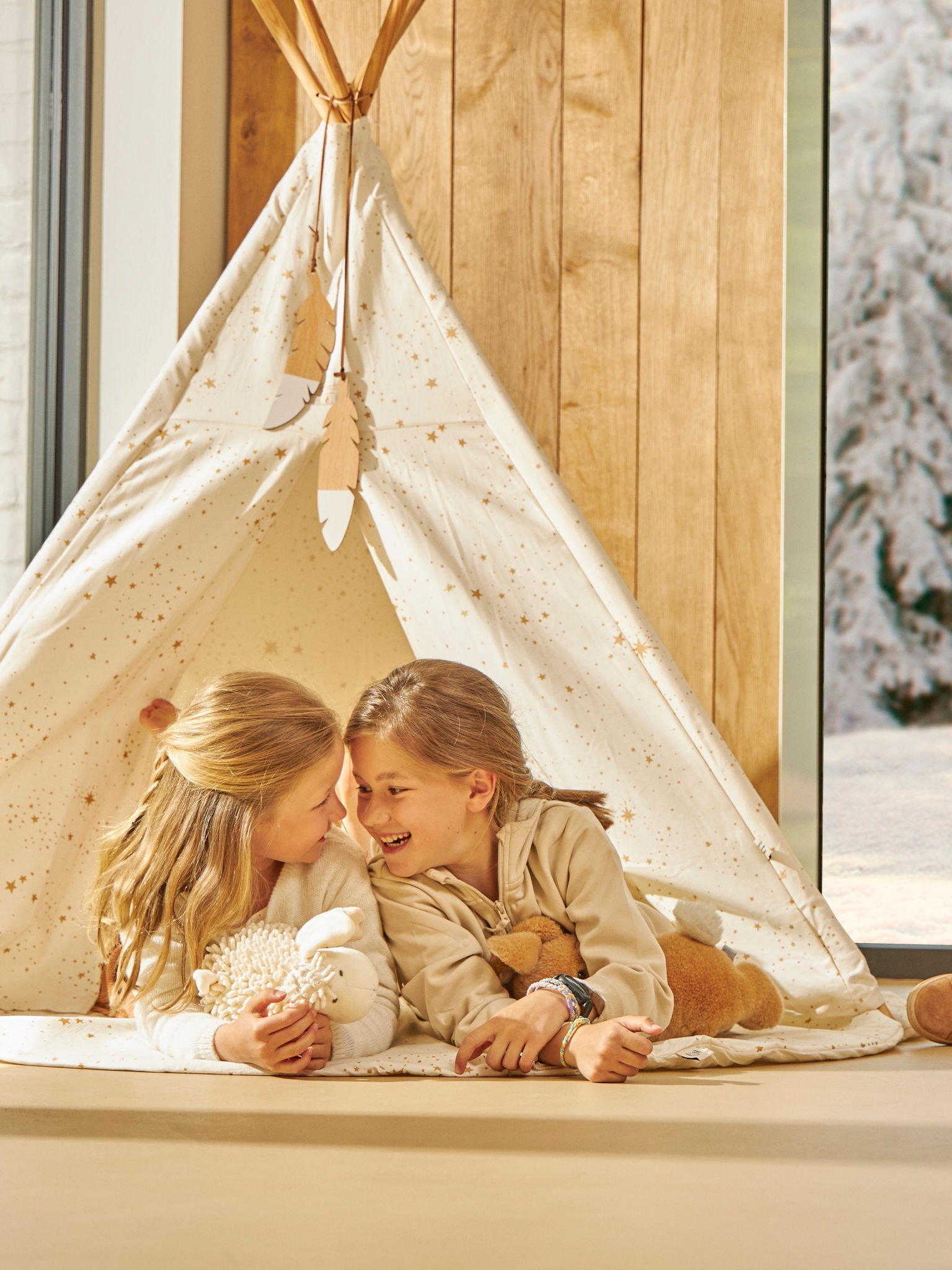 To små børn leger ubekymret i deres indendørstelt i en perfekt temperatur.