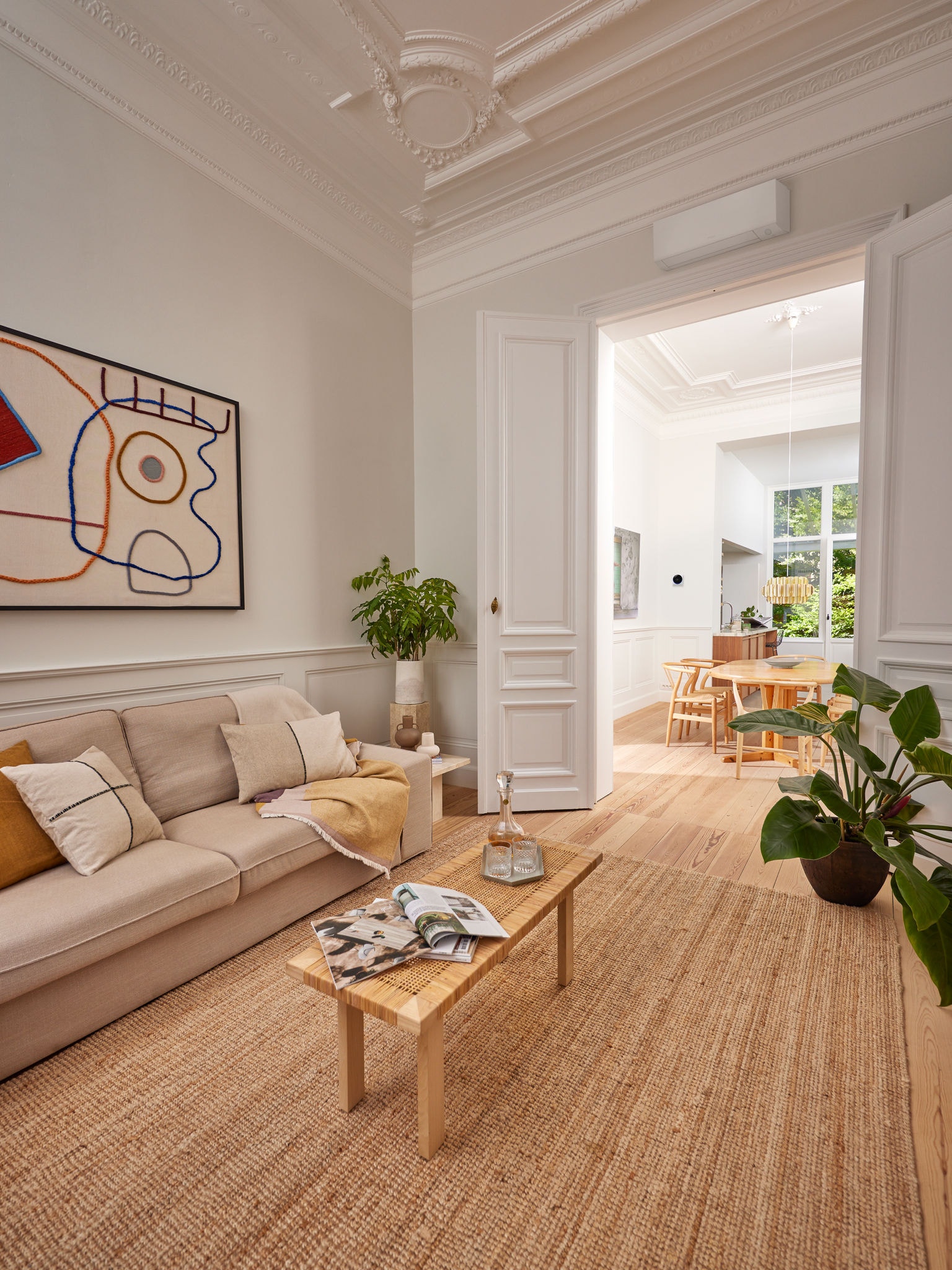 En elegant stue med en varmepumpe over en døråbning, som illustrerer, at statslige støtteordninger gør det mere overkommeligt at opvarme og køle boligen med en varmepumpe.