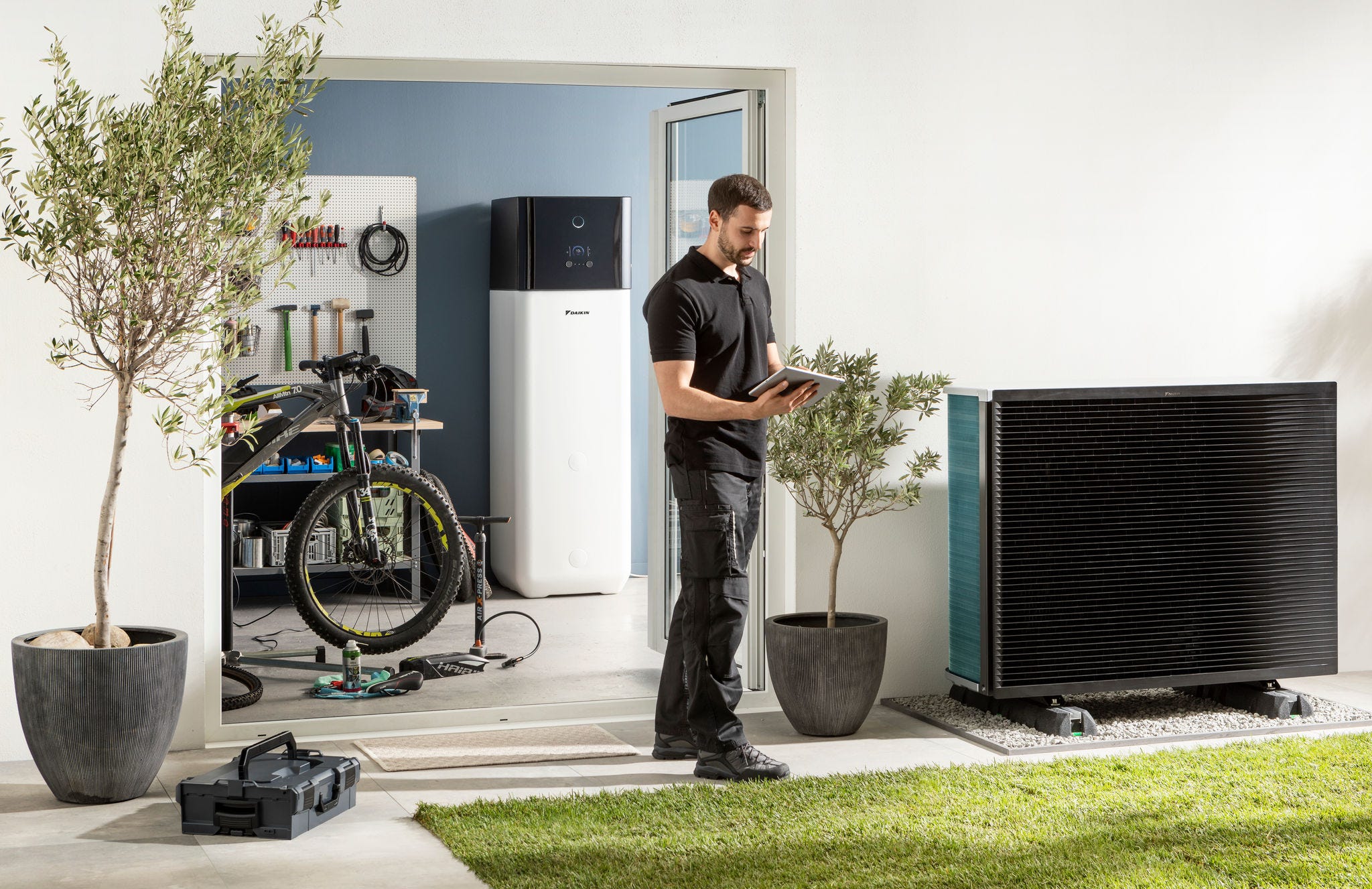 Installatør kontrollerer udendørsenhed til varmepumpe og varmevandsbeholder