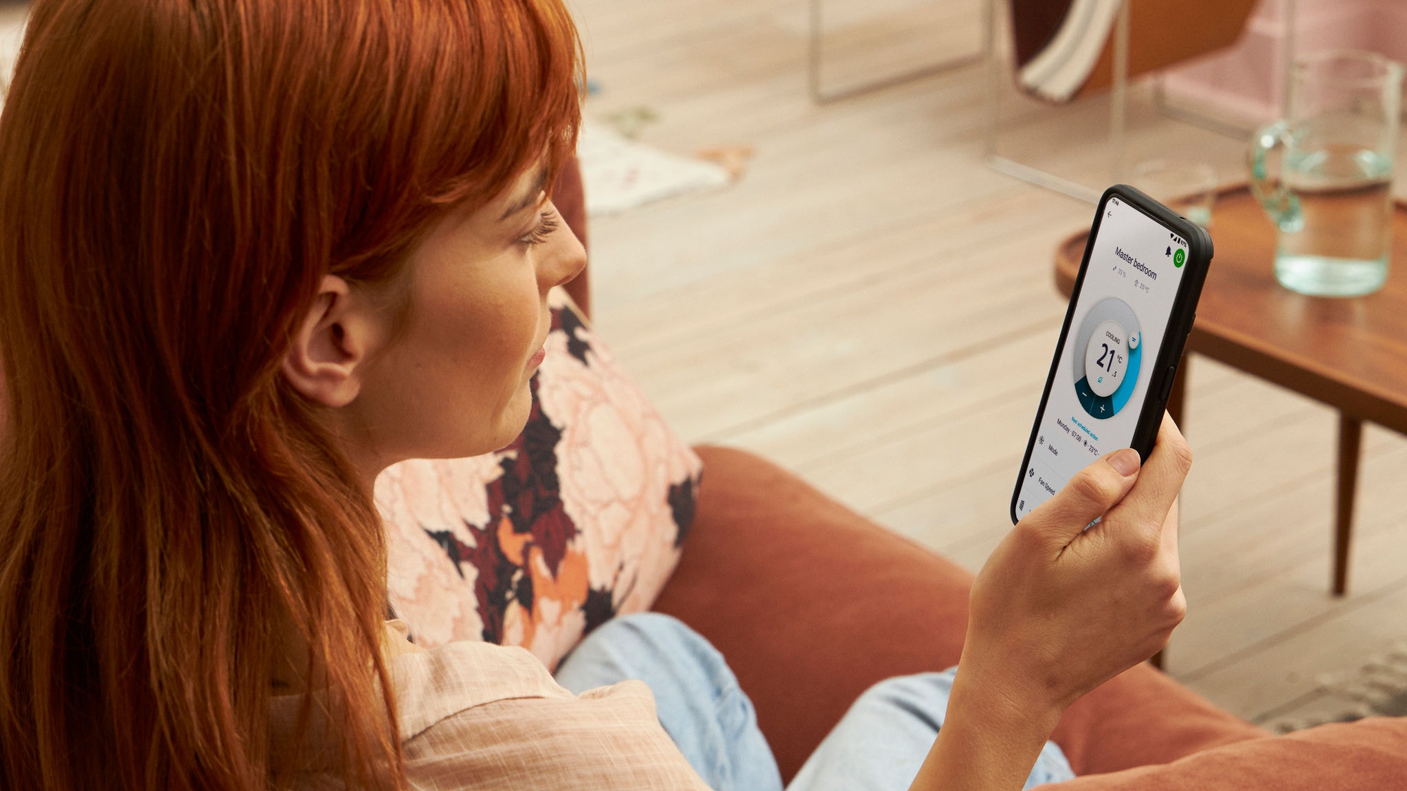 En kvinde bruger Onecta-appen i sin smartphone til at justere rumtemperaturen.