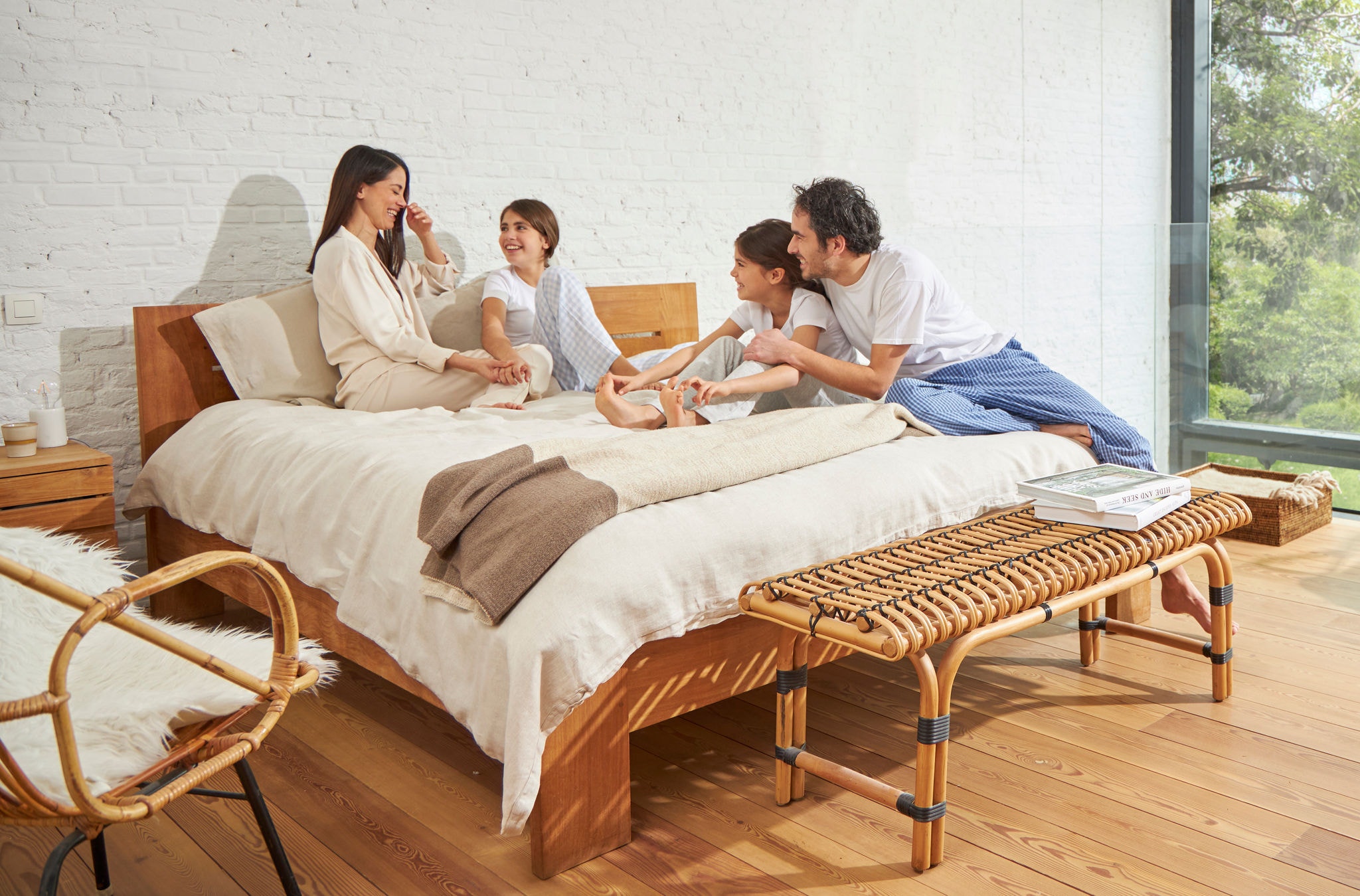 En kvinde og en mand sidder på en seng med to små piger og slapper af og ler, mens de nyder den rene luft.