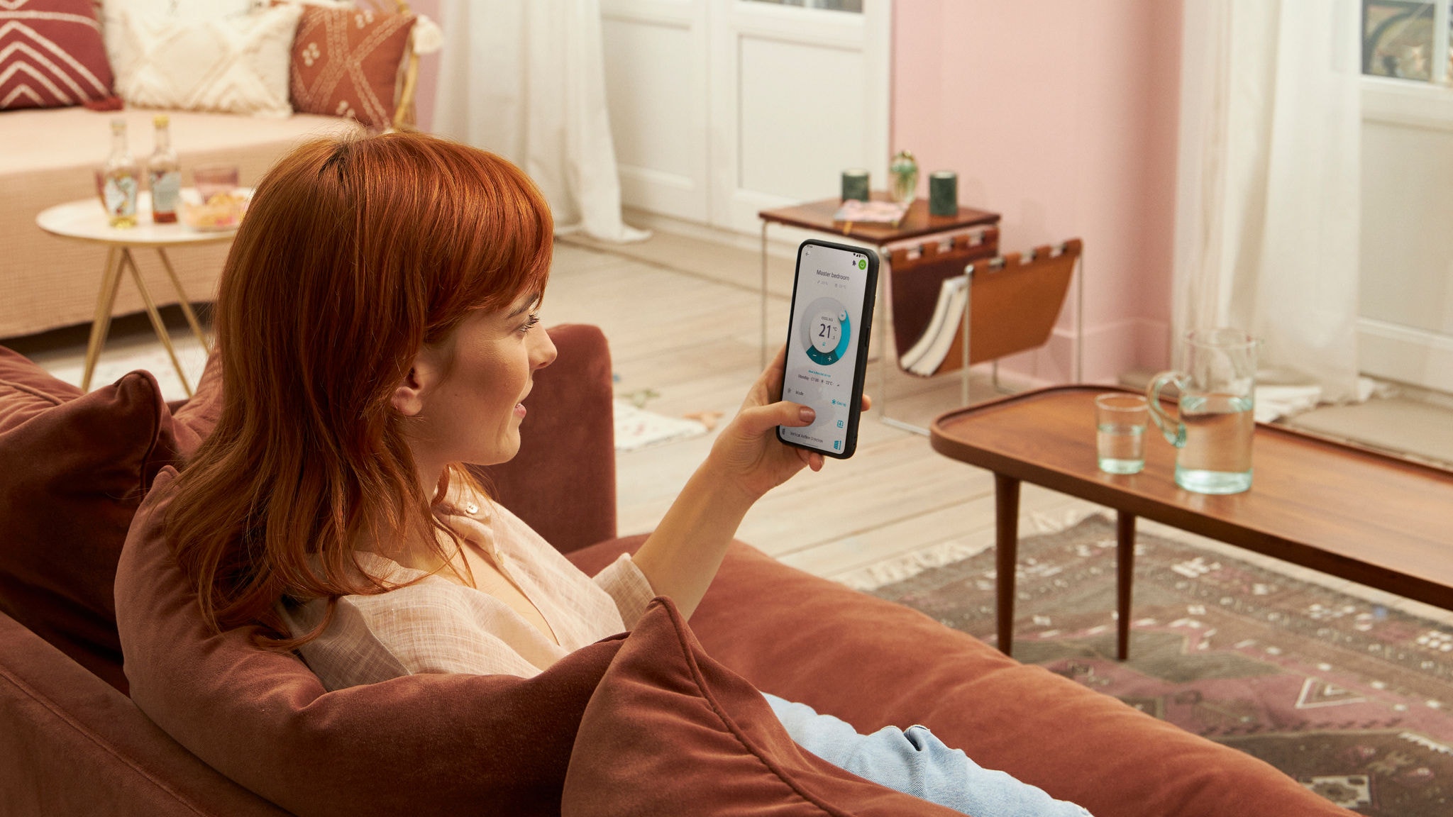 En kvinde sidder hjemme i sin sofa og bruger Onecta-appen på sin smartphone.