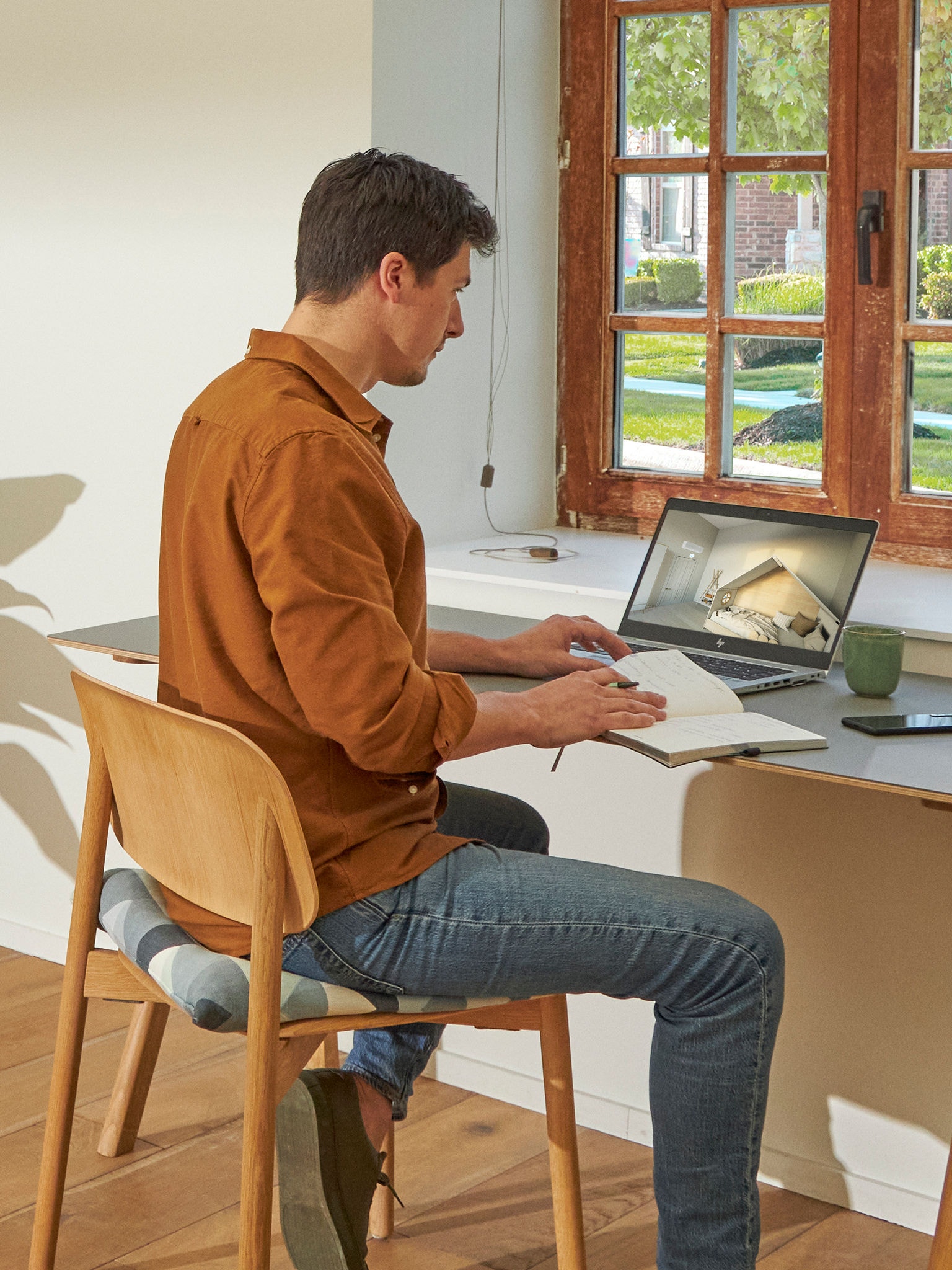 En mand sidder ved sit skrivebord og kigger på klimaanlæg, der vises i det virtuelle oplevelsescenter på hans bærbare computer.
