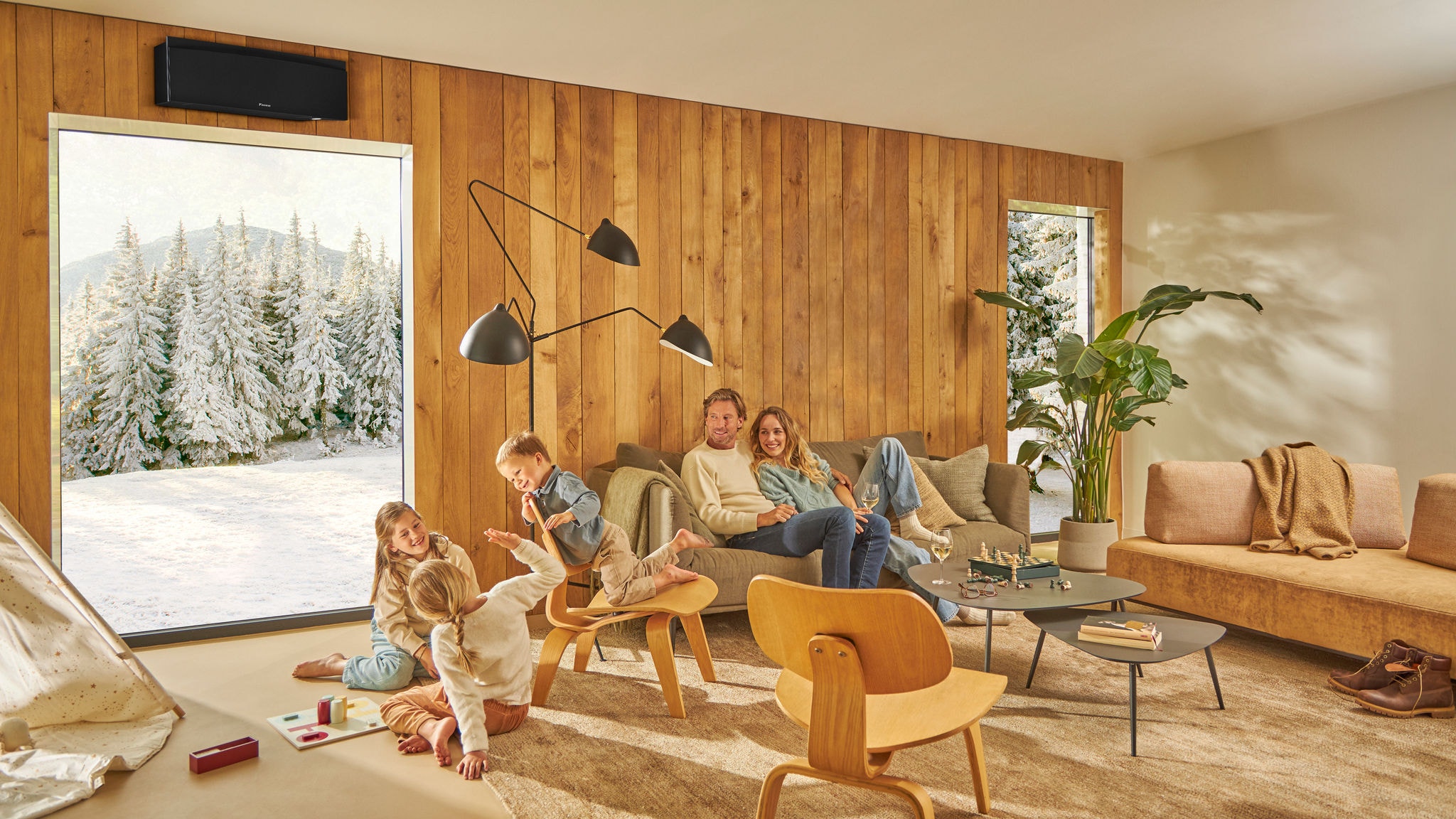 Familie på fire griner sammen, mens de spiller et brætspil i deres ventilerede køkken.