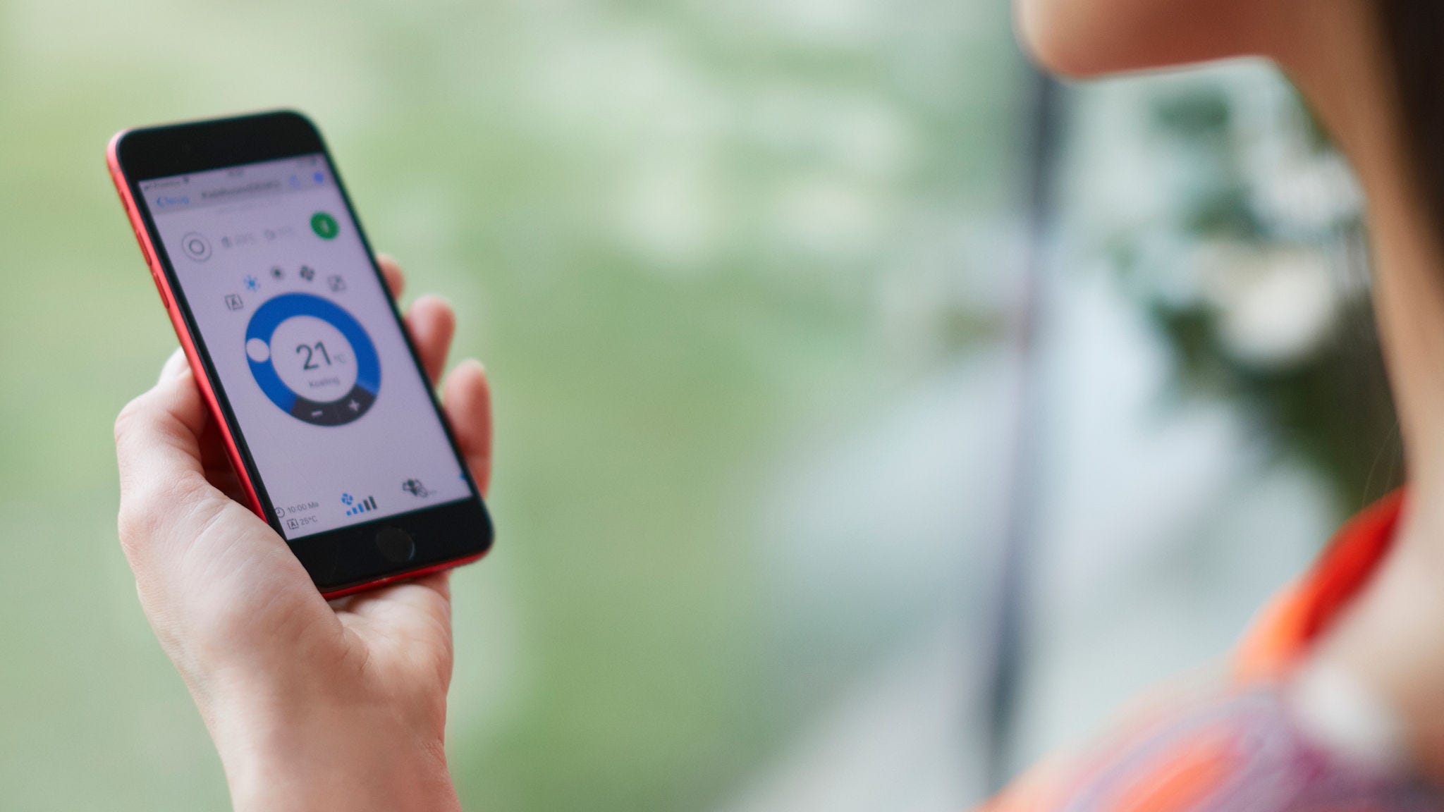 En kvinde bruger en app til at betjene sin varmningsløsning.