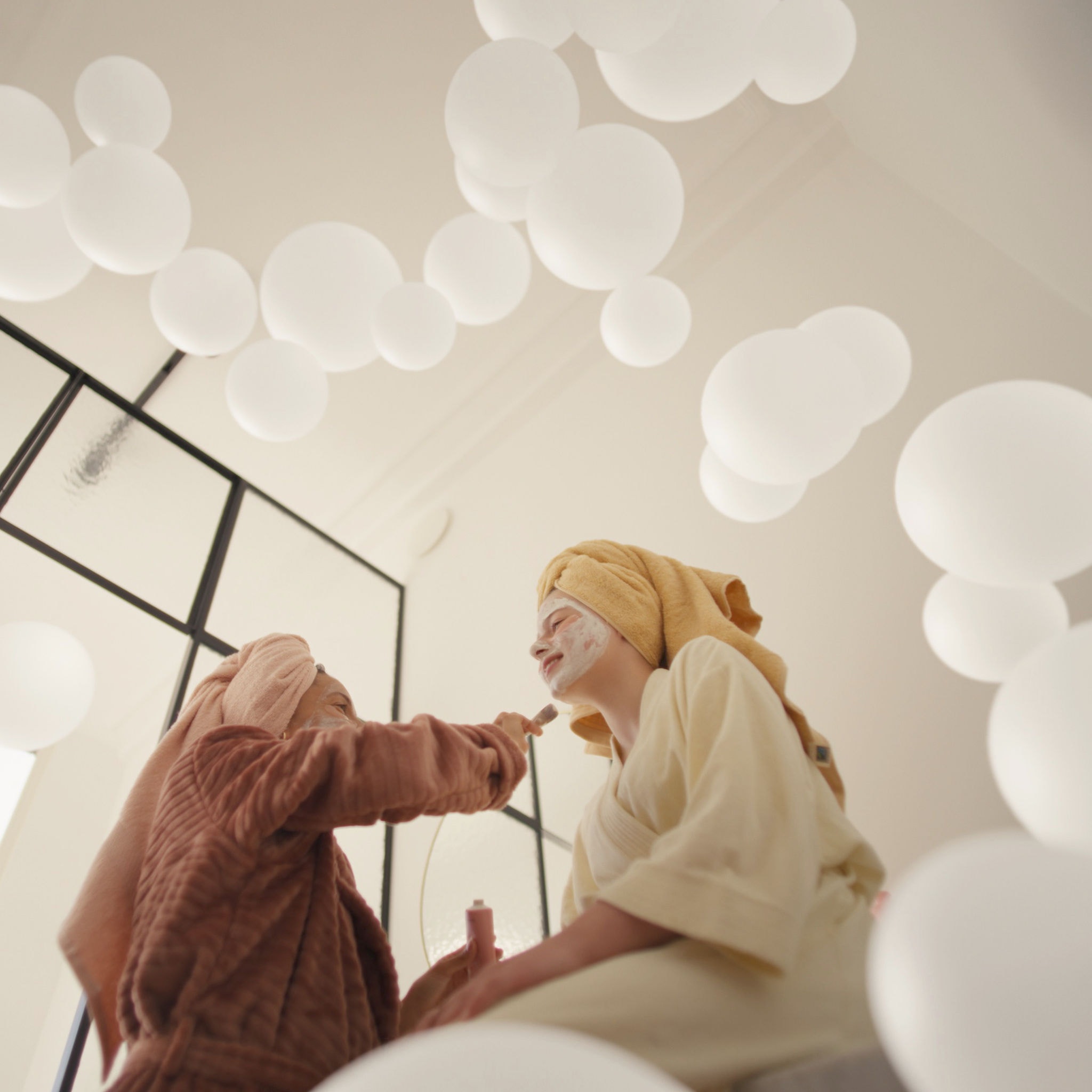 Mor og datter forkæler sig selv med ansigtsmasker i et godt ventileret rum takket være et ventilationssystem