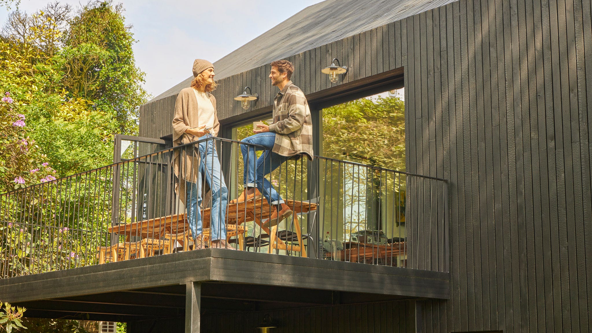 Et par taler sammen på en villaterrasse i grønne omgivelser