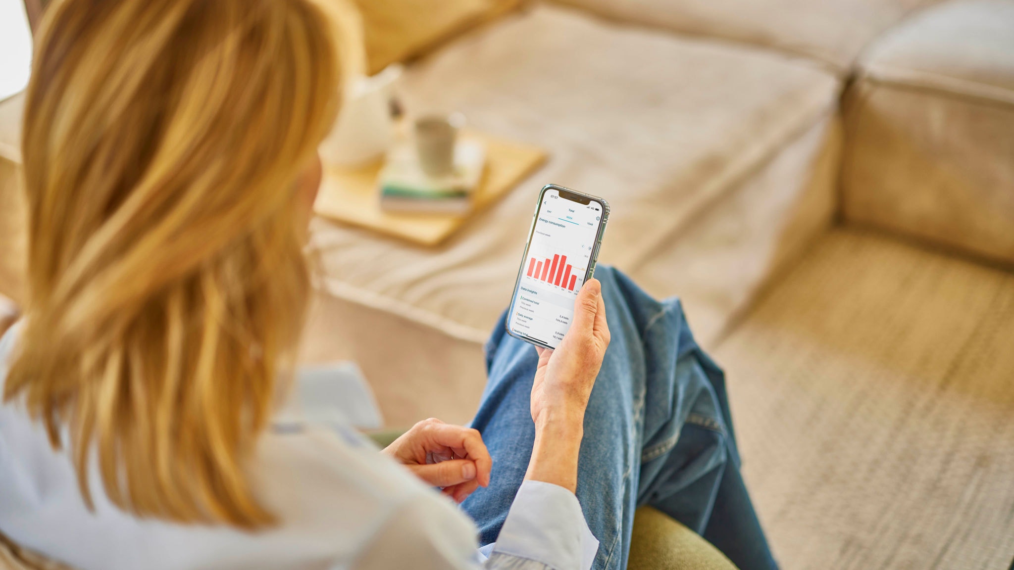 En kvinde betjener sit ventilationsanlæg ved hjælp af Onecta-appen