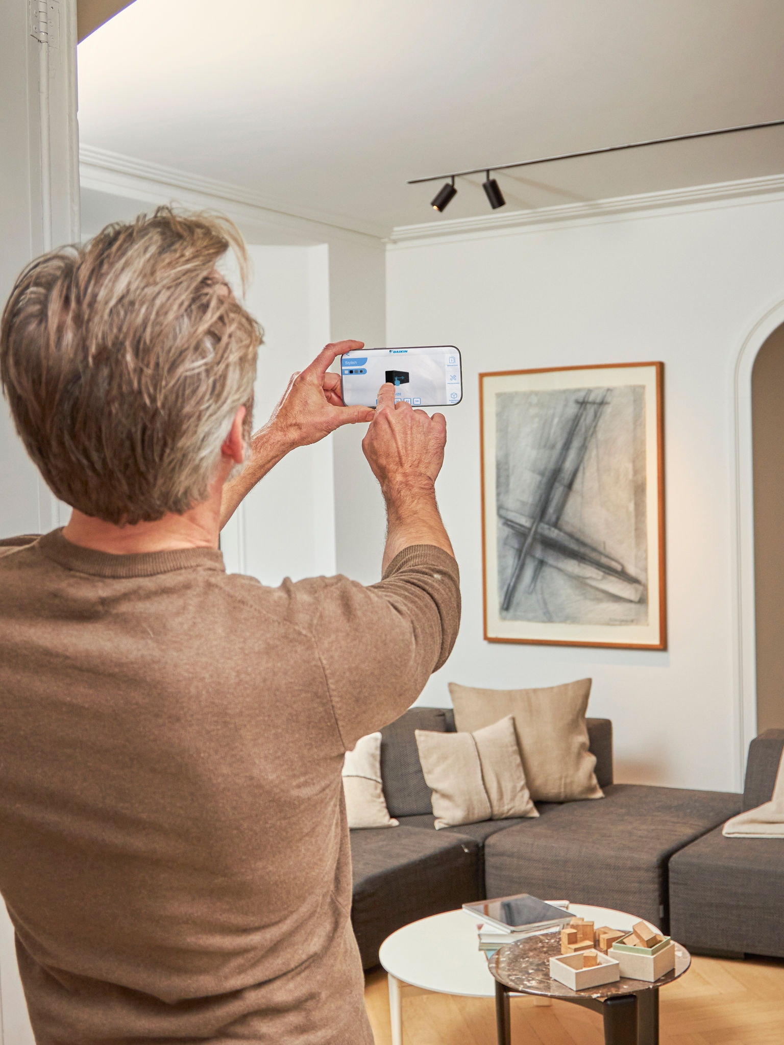 En mand bruger 3D-appen til at se en visualisering af luft-til-luft varmepumperne i augmented reality indendørs og udendørs hjemme hos sig selv.