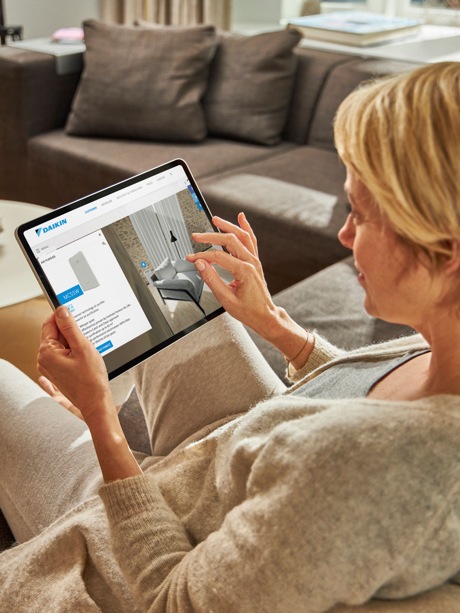 En person besøger det virtuelle oplevelsescenter for at se en luftrenser på en tablet.