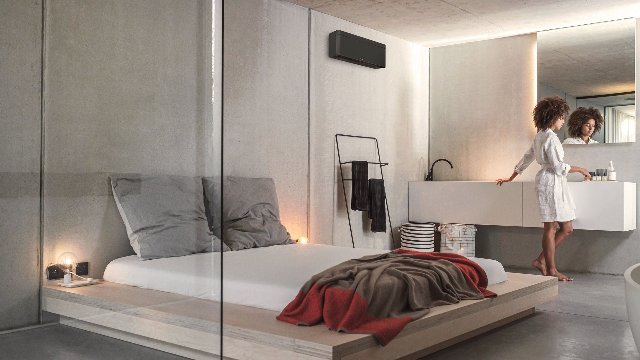 En kvinde gør sig klar i sit soveværelse med integreret badeværelse, som opvarmes og får frisk luft fra en Stylish-indendørsenhed.
